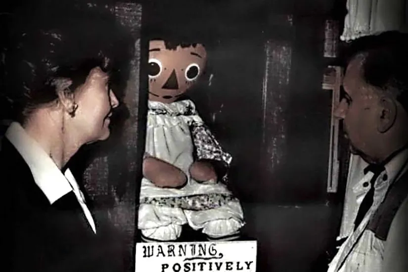 the warrens and the real annabelle doll in a glass case